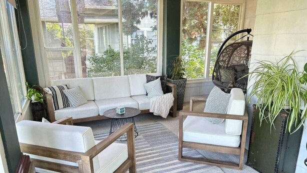 A sunroom with a sectional sofa, two armchairs, a coffee table, and a hanging chair.