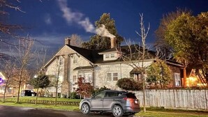 A house with a stone facade, a driveway, and a parked car.