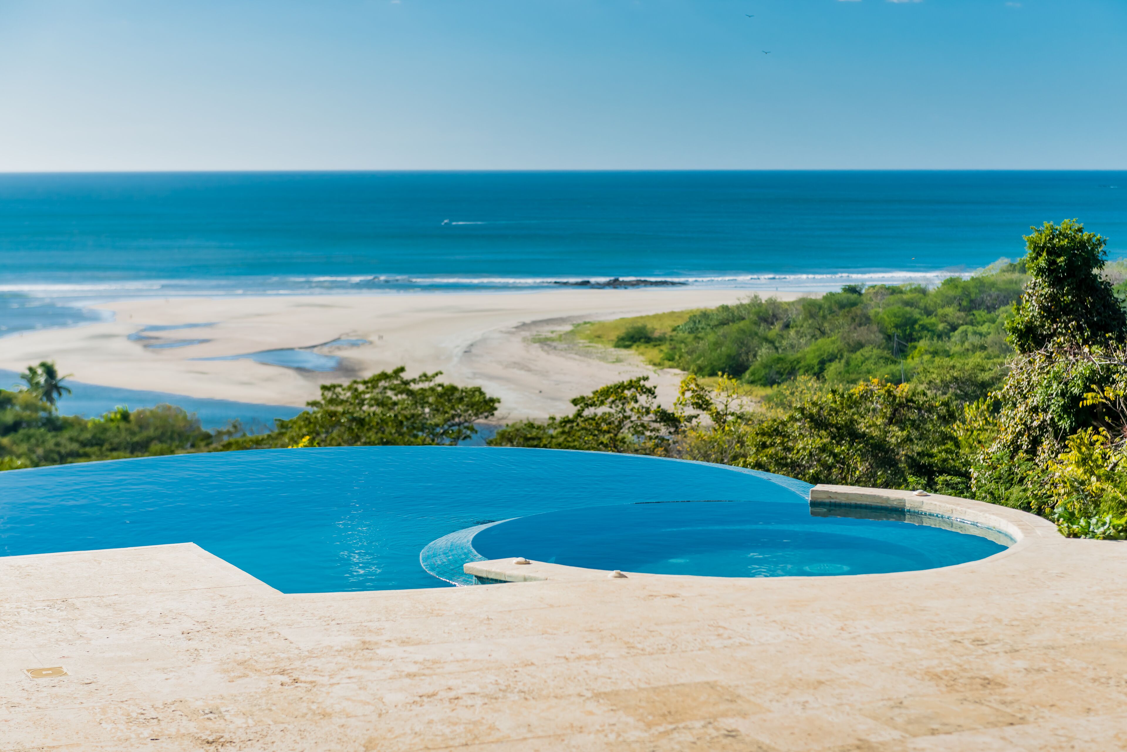 A infinity pool with a view of the ocean and beach.