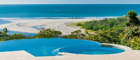 A infinity pool with a view of the ocean and beach.