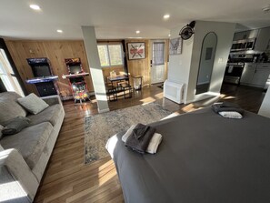 Ein modernes Interieur mit einer Couch, einem Bett, einem Essbereich und Spielautomaten.