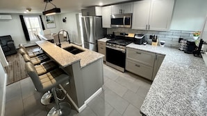 Una cocina moderna con electrodomésticos de acero inoxidable, encimeras de granito y una isla central.