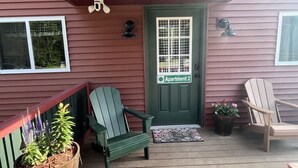 Un porche con dos sillas Adirondack, un felpudo y una puerta con la inscripción 'Apartment 2'.
