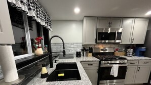 Una cocina moderna con encimeras de granito, electrodomésticos de acero inoxidable y armarios color gris claro.