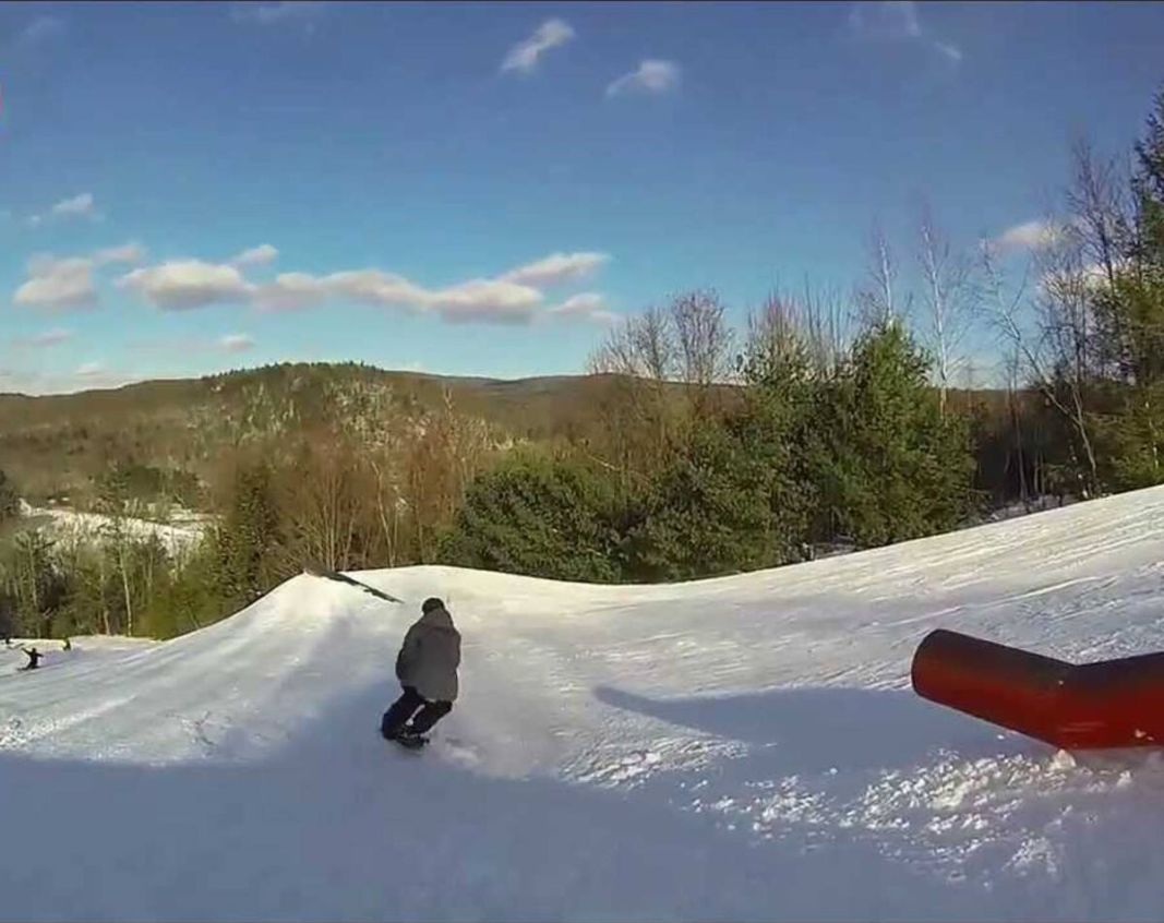 A snowy slope with a person snowboarding.