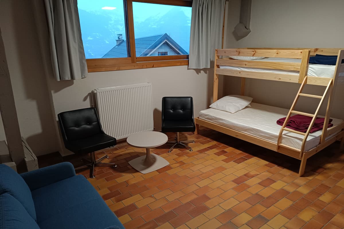 Ein Zimmer mit einem Etagenbett, zwei Stühlen, einem kleinen runden Tisch und einer Heizung.