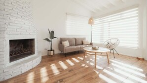 A living room with a white brick fireplace, a beige sofa, a round coffee table, and a chair. - Blvd Sunset. . . Beachfront Condos (Ensenada)