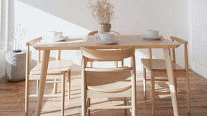 A dining area with a round table, six chairs, a hanging light fixture, and a vase with dried flowers. - Blvd Sunset. . . Beachfront Condos (Ensenada)