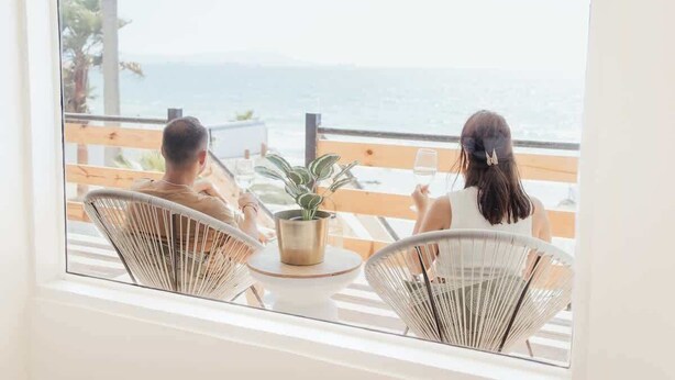 Two people sitting at a table with a view of the ocean. - Blvd Sunset. . . Beachfront Condos (Ensenada)