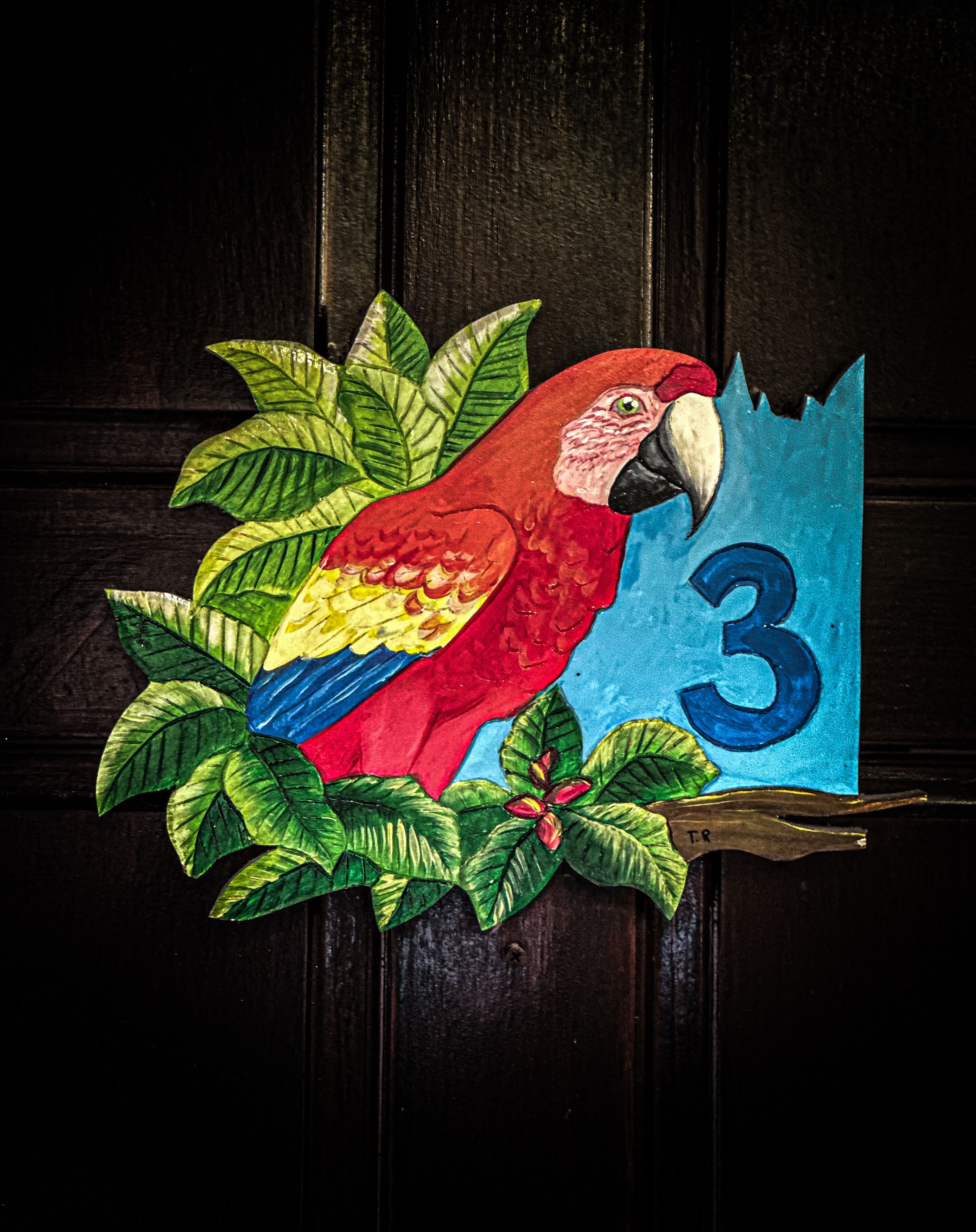 A colorful parrot decoration with a number '3' on a door.