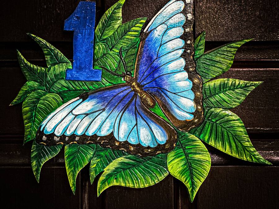 A stained glass window with a blue butterfly and leaves, and the number 1.