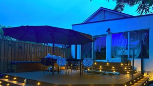 A wooden deck with outdoor seating, a large umbrella, and decorative lights. - River Runs Through It (Belleville)