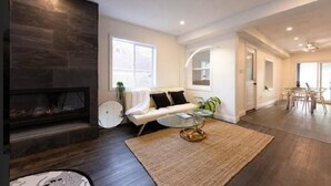 A modern living room with a fireplace, a sofa, a coffee table, and a dining area with chairs. - River Runs Through It (Belleville)