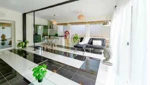 A modern interior with a glass partition, a dining area, and a seating area with a sofa and a table. - River Runs Through It (Belleville)
