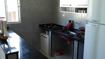 Een koelkast, een magnetron, een kookplaat, kookgerei, borden en bestek