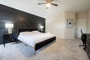 A bedroom with a bed, bedside tables, a ceiling fan, and a door. - 4BR | King Bed | World Cup Ready | 15 min to IAH (Houston)