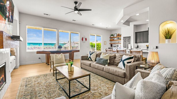 Een moderne woonkamer met een pooltafel, comfortabele zitplaatsen en uitzicht op het strand.