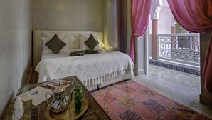 A hotel room with a bed, a table with a teapot and glasses, and a view of the outside balcony. - Riad Princesse Du Désert  (Marrakech)