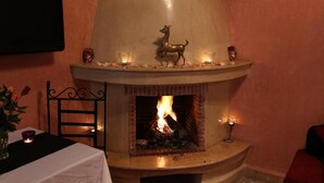 A fireplace with a deer decoration, lit candles, and a table with a white tablecloth. - Riad Princesse Du Désert  (Marrakech)