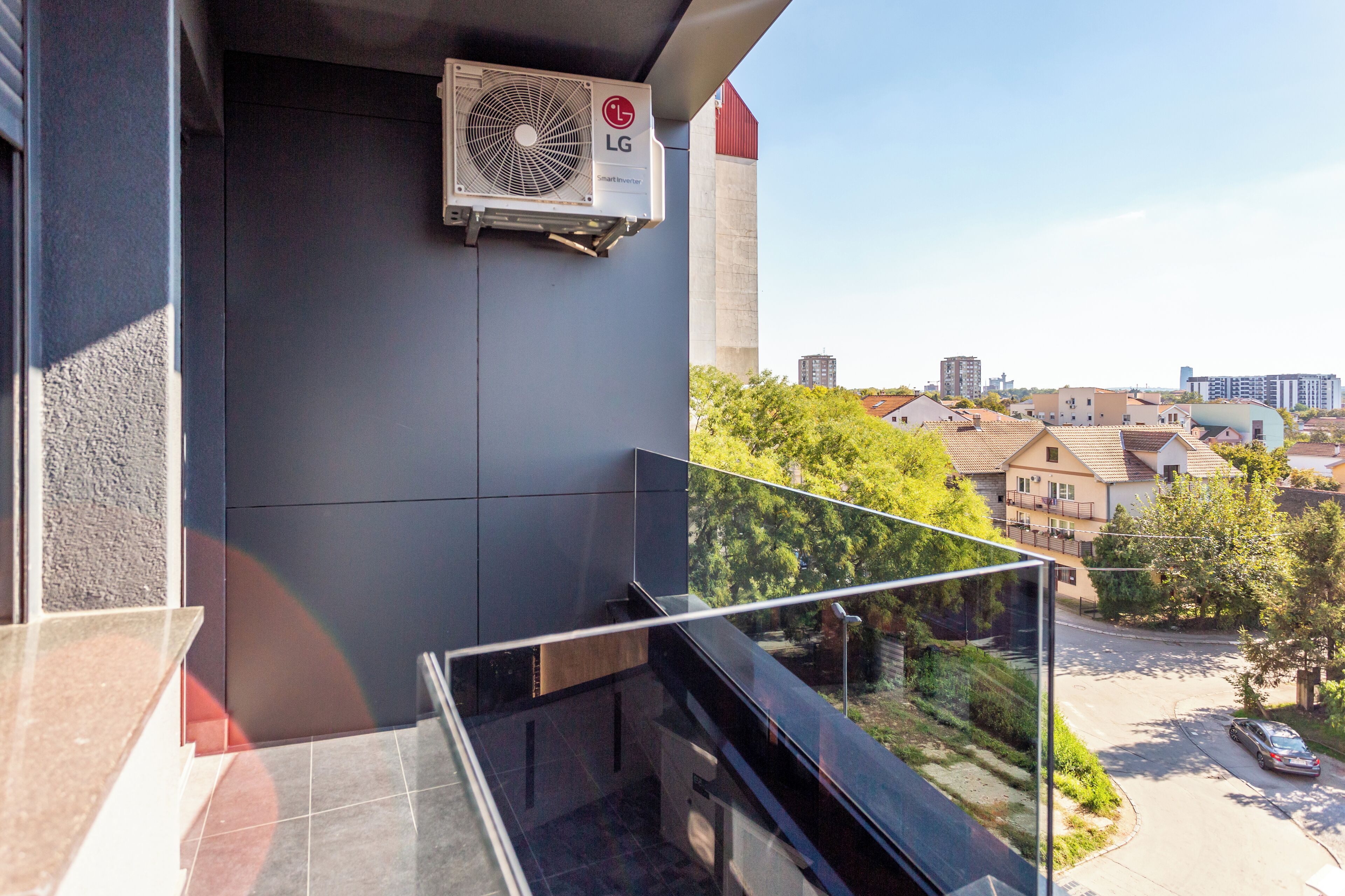 A modern balcony with a glass railing overlooking a residential area.