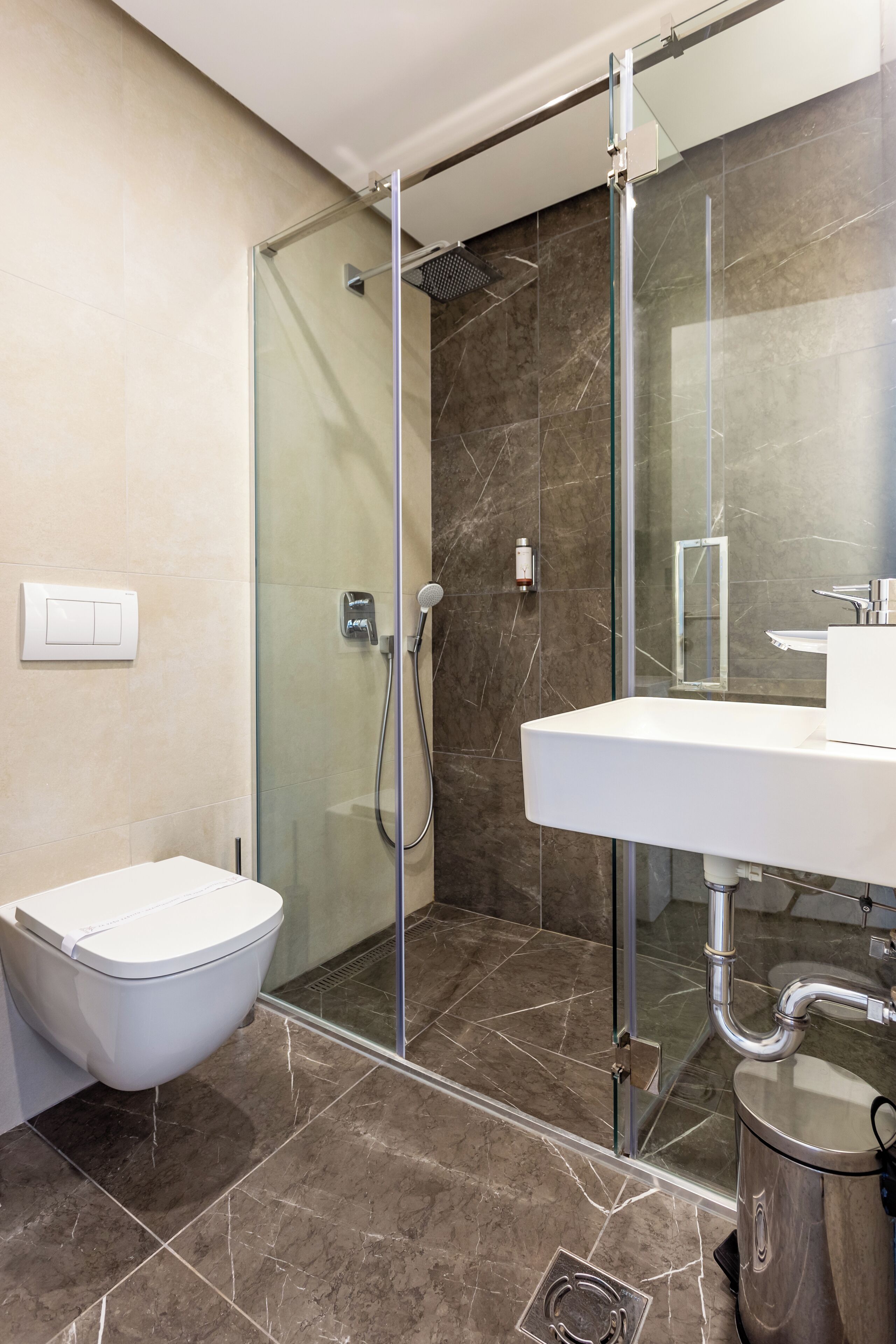A modern bathroom with a glass-enclosed shower, a white sink, and a toilet.