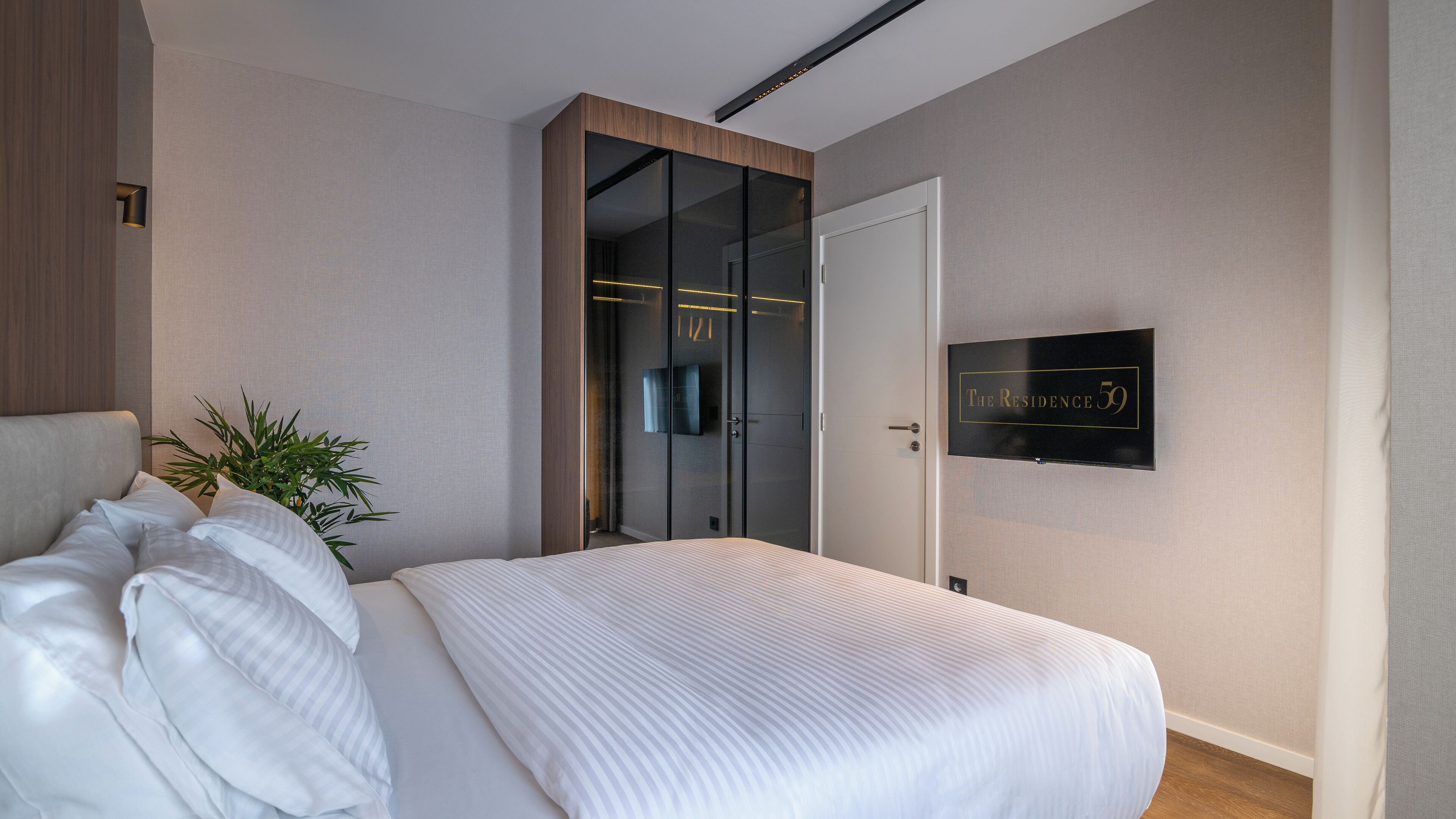 Une chambre moderne avec un grand lit, une armoire avec un miroir et une pancarte indiquant le numéro de chambre : 59.