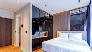 Un dormitorio moderno con una cama grande, un vestidor amplio y un ventanal espacioso.