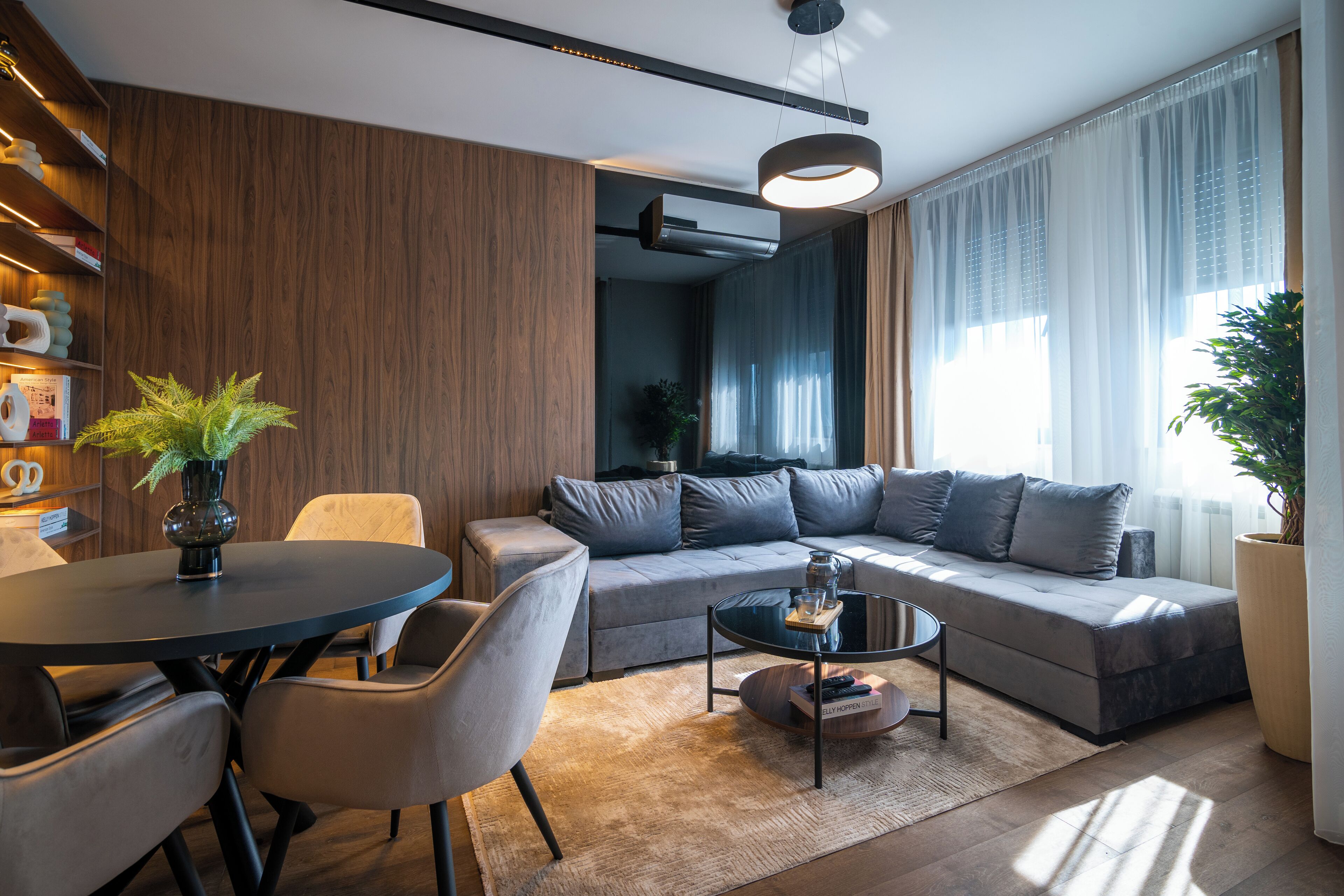 A modern living room with a sofa, a coffee table, and a dining area with chairs.