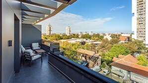 Un balcón moderno con vistas a un paisaje urbano, que incluye rascacielos y una mezcla de edificios residenciales y comerciales.