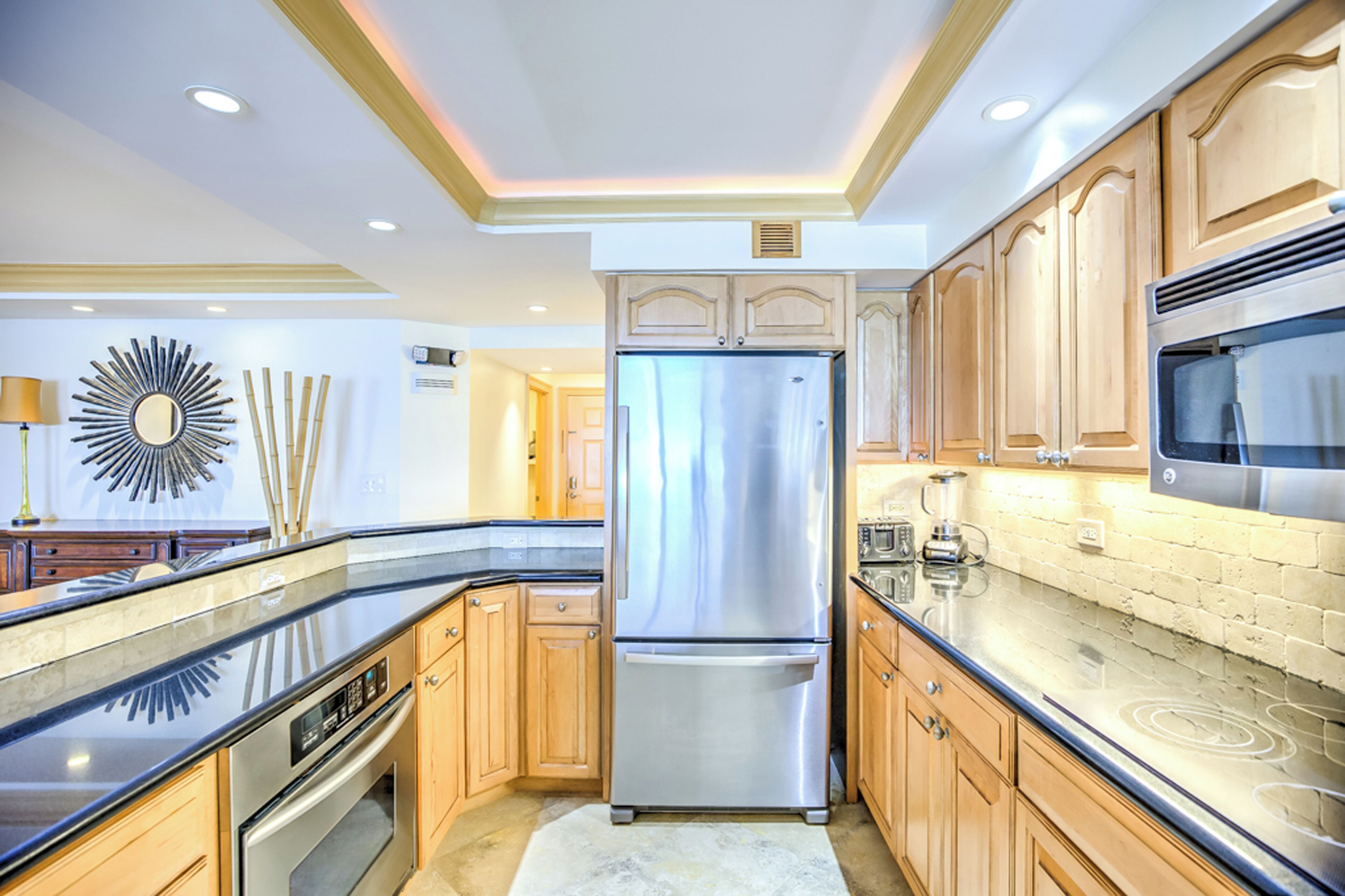 A modern kitchen with wooden cabinets, stainless steel appliances, and a black countertop.