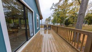 Une terrasse en bois avec une porte vitrée donnant sur un espace patio.