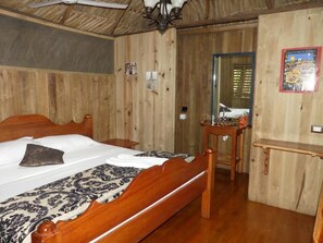 A wooden-paneled room with a bed, a small table, and a mirror. - Hotel Kangaroo y Restaurante (Livingston)