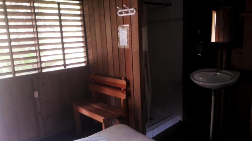 Una habitación con un banco de madera, ducha y lavabo.