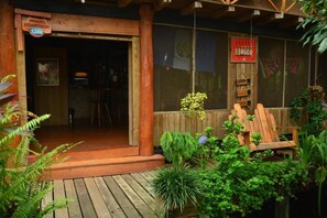 A wooden porch with a bench, surrounded by greenery. - Hotel Kangaroo y Restaurante (Livingston)