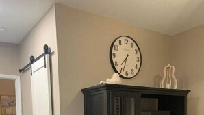 Ein Zimmer mit einem dunklen Holzschrank, einer Wanduhr und einer Schiebetür.