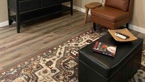 Ein Wohnzimmer mit einer schwarzen Unterhaltungsanlage, einem braunen Ledersofa, einem gemusterten Teppich und einer Uhr an der Wand.
