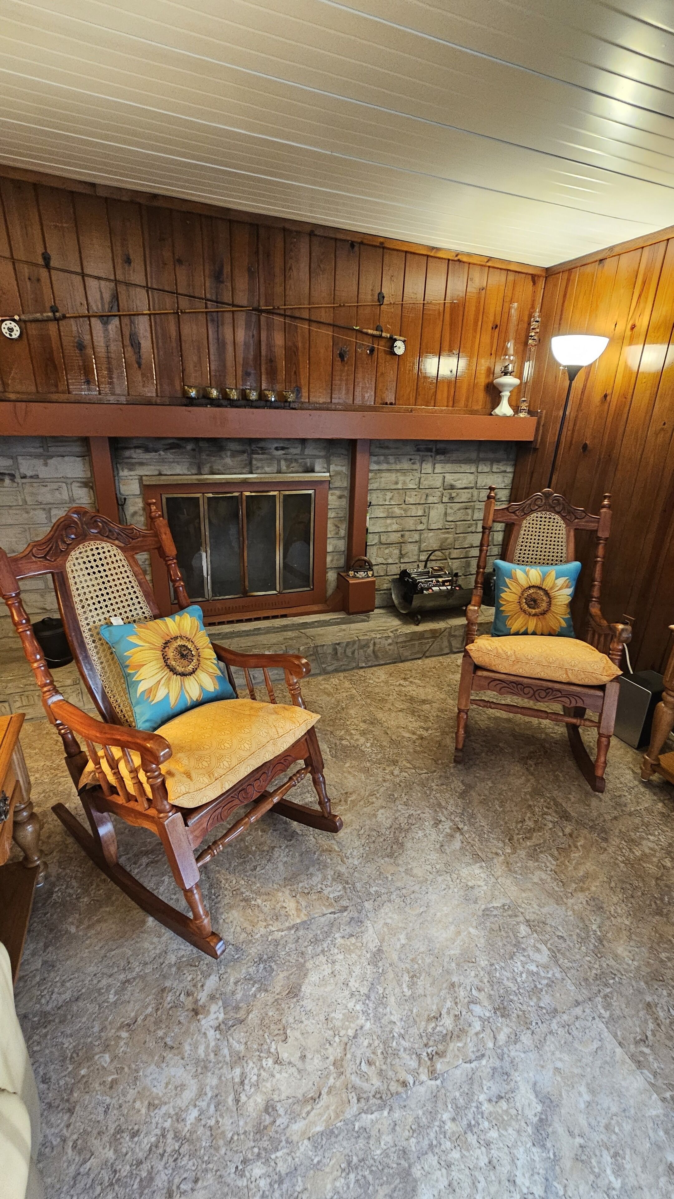 A cozy room with two rocking chairs, a stone fireplace, and a wooden ceiling.