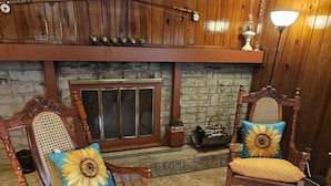 A cozy room with two rocking chairs, a stone fireplace, and a wooden ceiling.