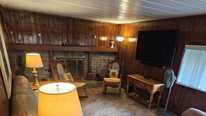 A cozy living room with a fireplace, leather sofa, wooden coffee table, and a television.