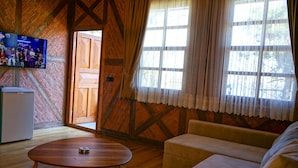 A cozy room with a wooden ceiling, a television, a sofa, and a window with curtains. - Sinop Bahçeler Villa (Sinop)