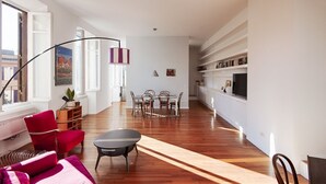 Ein modernes Wohnzimmer mit Essbereich, Holzboden und einem großen Fenster.