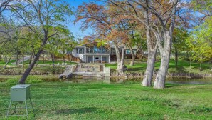 A modern house with a large deck, a pond, and a grassy area. - Turtle Creek House, 4 Bedrooms, 5 Bathrooms, only 8 miles south of Kerrville. (Kerrville)