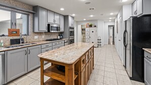 A modern kitchen with grey cabinets, stainless steel appliances, and a granite countertop island. - Turtle Creek House, 4 Bedrooms, 5 Bathrooms, only 8 miles south of Kerrville. (Kerrville)