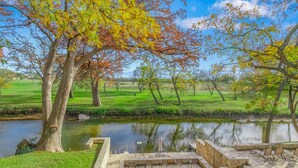 A serene outdoor area with a stone patio, seating, and a pond. - Turtle Creek House, 4 Bedrooms, 5 Bathrooms, only 8 miles south of Kerrville. (Kerrville)