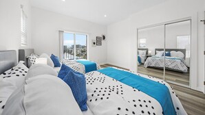 Een moderne slaapkamer met twee bedden, een groot raam en een schuifpui naar een balkon.
