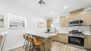 Een moderne keuken met een centraal eiland, barstoelen, een magnetron en een oven.