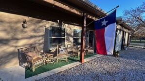 Un bâtiment doté d’un porche, de mobilier d’extérieur et arborant le drapeau du Texas.