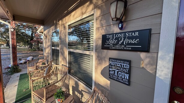 Une maison appelée « The Lone Star Lake House », dotée d’un porche, de fauteuils en osier et d’une pancarte indiquant qu’elle est protégée par la grâce divine et par une arme à feu.