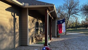 Une maison avec une véranda, un drapeau du Texas et deux alligators décorés.