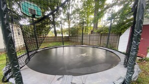Ein Trampolin mit Sicherheitsnetz im hinteren Garten.